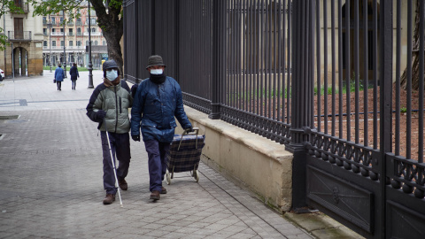 Una persona ciega camina junto a otra. 2020.