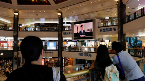 Varias personas escuchan el mensaje televisado de Carrie Lam en un centro comercial de Hong Kong. - REUTERS