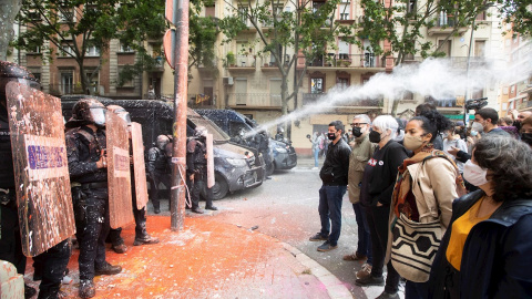 Policías antidisturbios de los Mossos d'Esquadra frente a las personas conventradas para evitar el desalojo del edificio conocido como Bloc Llavors, en el barrio del Poble Sec de Barcelona, que han lanzando objetos y pintura contra la línea