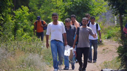 Varias personas caminan junto a un refugio temporal serbio en la frontera con Hungría. / EDVARD MOLNAR (EFE)