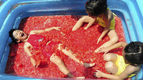 Unos niños juegan en una piscina llena de sandía para refrescarse en un parque de atracciones en Hangzhou, provincia de Zhejiang, China, 22 de julio de 2015. REUTERS / Stringer,