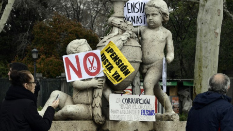 Una estatua del centro de Madrid con las pacartas y carteles de una manifestación de jubilados demandando mejores pensiones. AFP/Javier Soriano