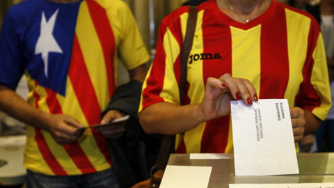 Una ciudadana deposita su voto en una mesa de en un colegio electoral de Barcelona durante el referéndum que tuvo lugar el 9-N del año 2014.- EFE