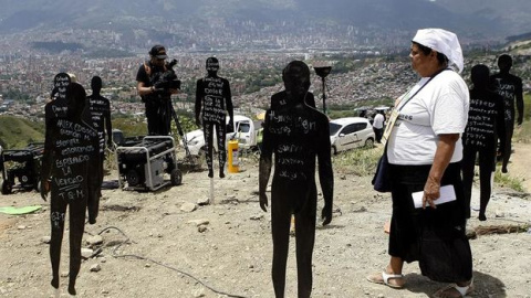 La familiar de uno de los desaparecidos de la Comuna 13, en Medellín, camina entre siluetas que representan a las víctimas enterradas en el lugar.