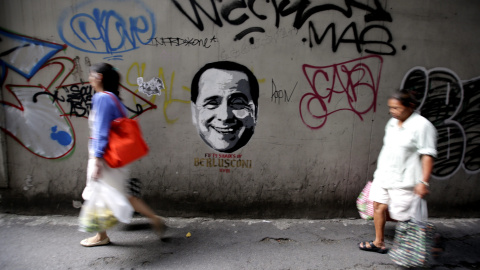 Fotografía de hoy, miércoles 29 de julio de 2015, que muestra a peatones pasando frente a un grafitti que reza " 50 Sombras de Berlusconi" bajo el rostro del ex Primer Ministro italiano Silvio Berlusconi en las calles de Bangkok (Tailandia)