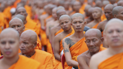 Varios monjes budistas participan en una ceremonia en la que los locales intentan hacer méritos a través de la entrega de flores, conocida como Tak Batdok Mai, al inicio de la cuaresma budista en las calles próximas al templo de Phra Phutth