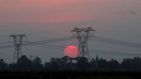 El sol se opne detras de unas torres de electricidad en Carletonville, al oeste de Johannesburgo. REUTERS/Siphiwe Sibeko