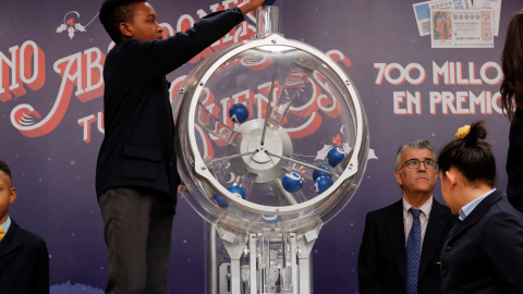 Uno de los niños de San Ildefonso intruduce las bolas en el bombo para el sorteo de la lotería de El Niño. EFE/ Zipi