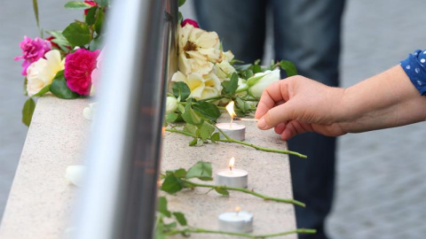 Una mujer enciende una vela en homenaje a las víctimas a la entrada del centro comercial donde se produjo el ataque. - EFE