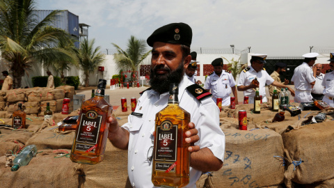 Un oficial de la Agencia de Seguridad Marítima de Pakistán (PMSA) sostiene dos botellas de alcohol durante la demostración de botellas de licor en Karachi, Pakistán. REUTERS/Akhtar Soomro