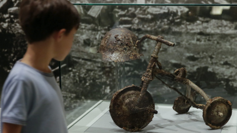 Un niño observa un triciclo y un casco expuestos en el Museo de la Paz en el Parque de la Paz de Hiroshima, al oeste de Japón. El triciclo perteneció al joven Shinichi Tetsuya, que montaba en él cuando la bomba cayó. EFE/Kimimasa Mayama