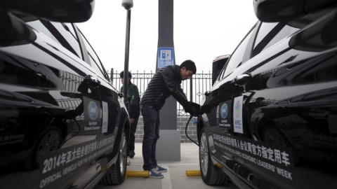 Un hombre carga las baterías de los autos eléctricos en Pekín. REUTERS