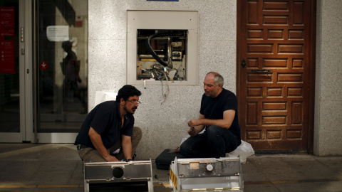 Fos operarios reparan un cajero automático en un banco en Ronda (Málaga). REUTERS/Jon Nazca