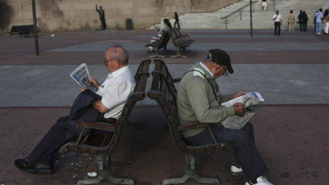 Dos pensionistas leen el periódico en un banco en Madrid. REUTERS