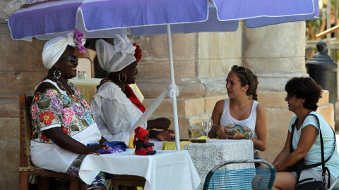 Dos turistas consultan su futuro con cartománticas en La Habana. Toparse con visitantes de Estados Unidos por La Habana es cada vez más habitual, atraídos por los coches antiguos que todavía circulan por su calles y sus edificaciones anteri