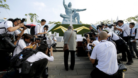 Los fotógrafos rodean a una anciana que reza delante del monumento a las víctimas de Nagasaki, frente al Momumento a la Paz, en la ciudad japonesa, que celebra el 70 aniversario de la biomba atómica. REUTERS/Toru Hanai