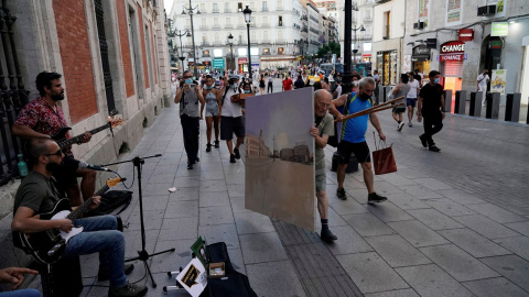 El pintor Antonio López lleva el lienzo en el que está pintando la Puerta del Sol de Madrid después de una jornada de trabajo en la misma plaza. REUTERS / Juan Medina