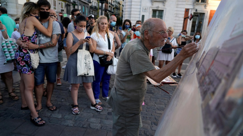 Varias personas observan trabajar al pintor  Antonio Lopez en la céntrica Puerta del Sol de  Madrid. REUTERS/Juan Medina