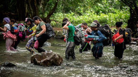 Un grupo de migrantes atraviesa un río durante su travesía por la selva del Darién, que separa Colombia de Panamá.