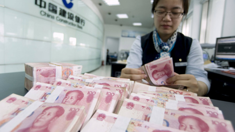 Una cajera del banco chino CCB cuenta billetes de yuan. REUTERS/China Daily