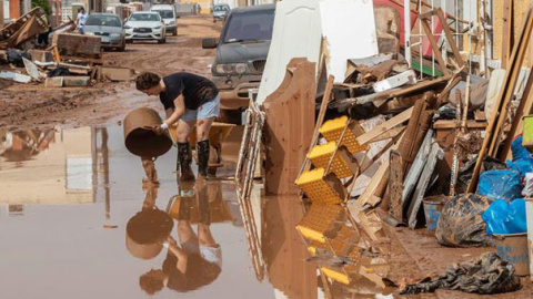 Una mujer vierte lodo en Cartagena, afectada por las inundaciones provocadas por las lluvias caídas en Murcia. / EFE