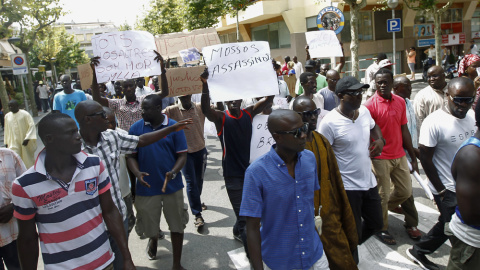 Inmigrantes senegaleses muestran pancartas contra la los Mossos D'esquadra en la manifestació en Salou para protestar por la muerte de un compatriota en una operación contra el 'top manta'. AFP PHOTO / QUIQUE GARCIA