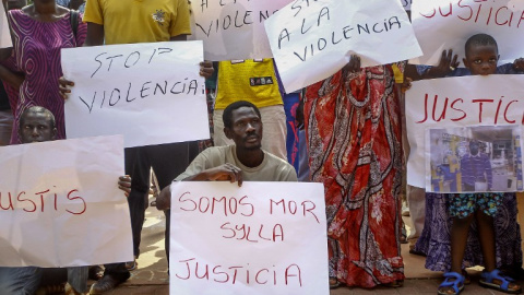 Inmigrantes senegaleses muestran pancartas contra la los Mossos D'esquadra en la manifestació en Salou para protestar por la muerte de un compatriota en una operación contra el 'top manta'. AFP PHOTO / QUIQUE GARCIA