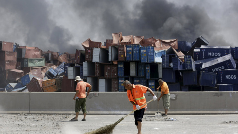 Varios empleados chinos trabajan para limpiar de piedras y polvo una carretera cerca del lugar de la explosión. REUTERS