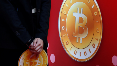 Un empleado de la tienda bitcoin de Hong Kong sostiene el logo de la moneda virtual. REUTERS/Bobby Yip