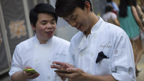 Dos empleados disfrutan del videojuego "Pokémon GO" mientras realizan un descanso durante el lanzamiento del juego en Hong Kong, China. EFE/JEROME FAVRE