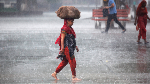 Una mujer lleva un saco fuera de un mercado durante las fuertes lluvias en Chandigarh, India. REUTERS/Ajay Verma