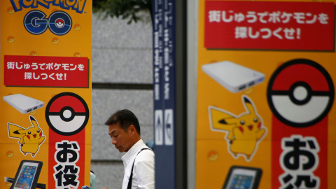 Un hombre utiliza su teléfono móvil enfrente de un anuncio con la imagen del juego Pokémon GO en una tienda de Tokio, Japón. REUTERS/Kim Kyung-Hoon