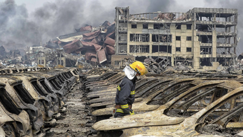 Un bombero, entre vehículos calcinados junto al almacén incendiado. - REUTERS