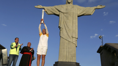 La jugadora de voleibol Isabel Barroso levanta la antorcha ante el Cristo Redentor. /REUTERS