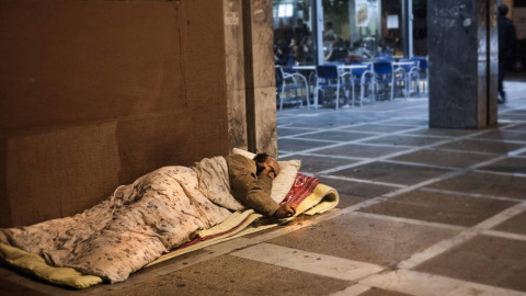 Un hombre durmiendo en un el suelo de la calle. EFE