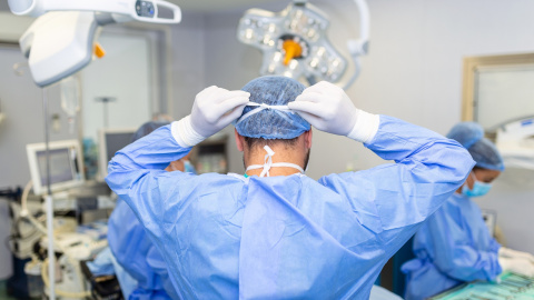 Vista trasera del cirujano masculino con mascarilla quirúrgica en el quirófano del hospital