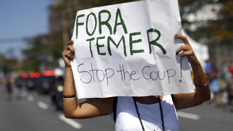 Un manifestante sujeta una pancarta en contra de Temer durante el recorrido de la antorcha olímpica en la playa de Copacabana en Río de Janeiro, Brasil. REUTERS/Benoit Tessier