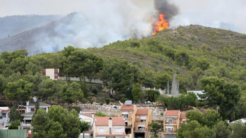 Imagen del incendio en La Pobla de Montornès (Tarragona) donde los Bomberos han desalojado hoy la parte alta de la urbanización Castell de Montornès como medida de precaución ante un incendio que arde sin control en una zona forestal de dif