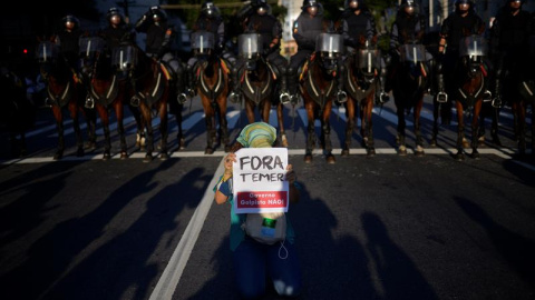 Policías brasileños y un manifestante con una pancarta en la que se reza "Fuera Temer", durante una protesta contra los Juegos Olímpicos. EFE/FAVIO TEIXEIRA