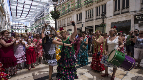 Un grupo de mujeres ataviadas con trajes flamencos tocan y bailan en la popular calle Larios de la Feria malagueña. EFE/Jorge Zapata