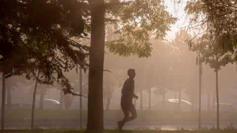 Un hombre corre entre la neblina por la mañana en Vitoria.