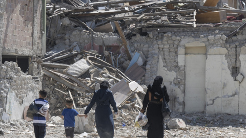 Imagen de archivo de un dos mujeres y dos niños caminando entre los escombros de uno de los 6.000 edificios que derrumbaron los terremotos de Turquía en febrero de 2023.