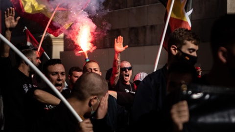 Jóvenes neonazis con bengalas levantan el brazo durante una manifestación neonazi para celebrar el día de la Hispanidad, a 12 de octubre de 2021, en Barcelona.