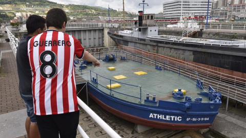 Dos jóvenes observan la legendaria gabarra con la que el Athletic Club celebró sus títulos en 1983 y 1984. EFE/ Miguel Toña