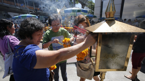 Turistas malasios queman incienso ante el altar del templo de Erawan donde el pasado lunes estalló una bomba en Bangkok.- EFE