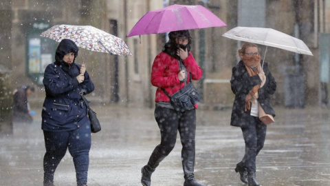 Imagen de archivo de varias personas transitan bajo la lluvia la plaza del Obradoiro, en Santiago de Compostela/EFE