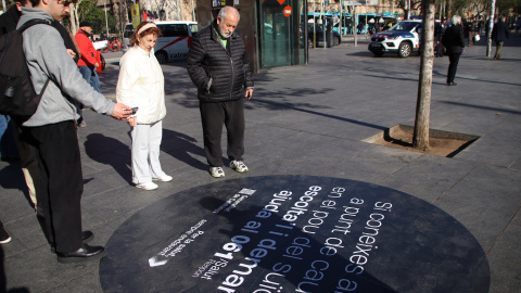 Diverses persones llegeixen el missatge del vinil de plaça Universitat