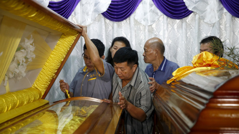 Un herido en el atentado del lunes en Bangkok, junto a los ataúdes de su esposa e hijo, muertos en la explosión.- REUTERS / Olivia Harris