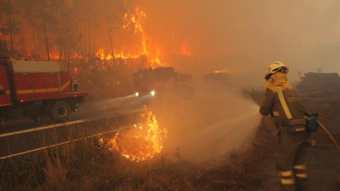 Un bombero muy cercano al fuego intenta apagarlo con una manguera en Santiago de Compostela/EFE