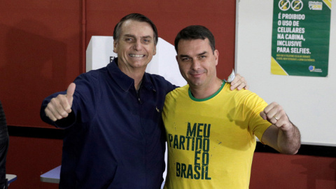 Jair Bolsonaro, y su hijo, Flávio, tras depositar su voto en las elecciones, Río de Janeiro, Brasil, 7 de octubre de 2018. / Ricardo Moraes / Reuters